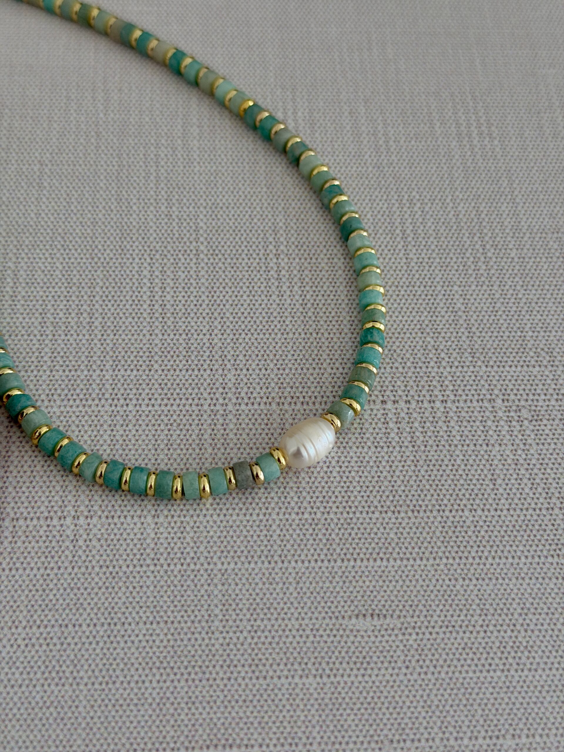 Aquamarine beads separated by gold plated spacer beads with a center focal of freshwater pearl