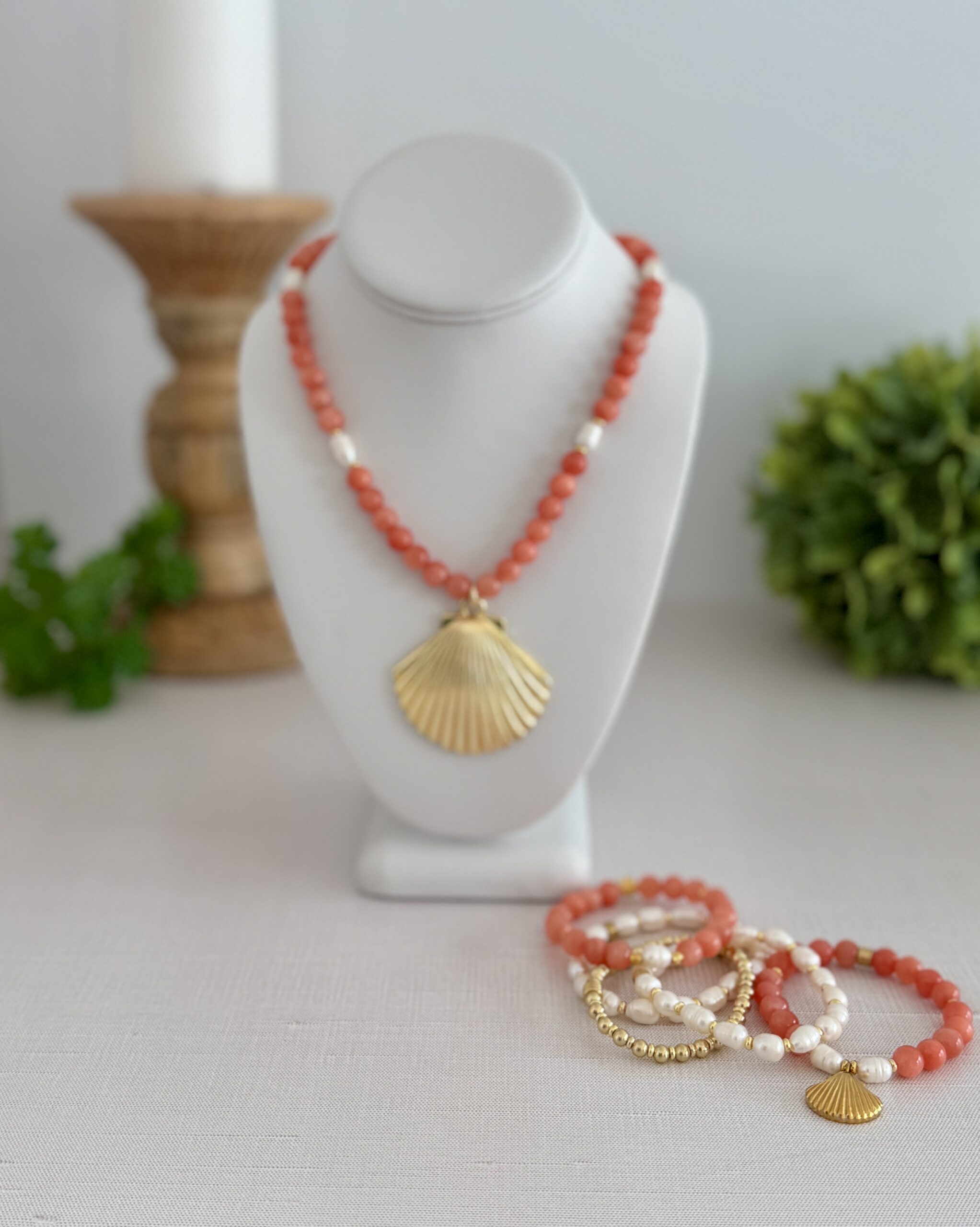 18” necklace of Botswana Agate in an orange red tones. Freshwater pearls and a gold plated shell pendant are centered.