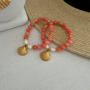 Coral colored Botswana agate gemstone bracelet with freshwater pearls. Centered is a gold plated scallop shell charm.