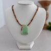 A large green varisite stone pendant sits centered on the hessonite garnet necklace. The length is 17” and the clasp is a lobster style closure.