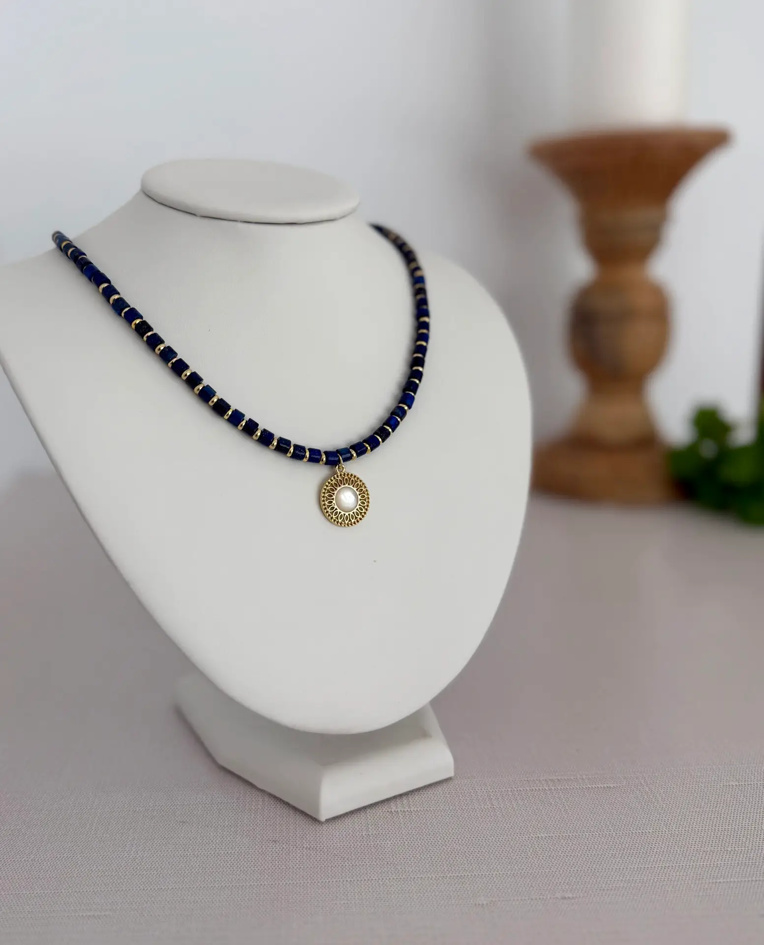 Blue lapis lazuli beads separated by gold disk spacers. 16” with a round gold and moonstone medallion in the center. The clasp is a lobster style closure