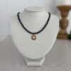 Blue lapis lazuli beads separated by gold disk spacers. 16” with a round gold and moonstone medallion in the center. The clasp is a lobster style closure