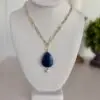 Blue Lapis Lazuli teardrop pendant hanging from a gold plated paper clip chain. The necklace is 17” the clasp is a lobster style. A fresh water pearl hangs from the bottom of the lapis pendant