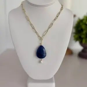 Blue Lapis Lazuli teardrop pendant hanging from a gold plated paper clip chain. The necklace is 17” the clasp is a lobster style. A fresh water pearl hangs from the bottom of the lapis pendant