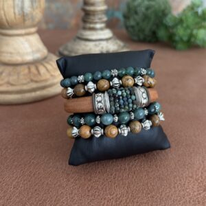 Green Tourmaline leather bracelet set. The leather is Portuguese in a caramel tone. The tourmaline beads are hand sewn around the leather in the center of the bracelets. There are silver spacers to the left and right of the beads. This frames the gems nicely. The clasp is in a magnetic style. The four remaining bracelets are stretch in style. Two are in picture Jasper round beads 8mm in size. Two are in deep green jade.