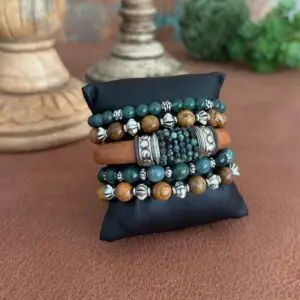 Green Tourmaline leather bracelet set. The leather is Portuguese in a caramel tone. The tourmaline beads are hand sewn around the leather in the center of the bracelets. There are silver spacers to the left and right of the beads. This frames the gems nicely. The clasp is in a magnetic style. The four remaining bracelets are stretch in style. Two are in picture Jasper round beads 8mm in size. Two are in deep green jade.