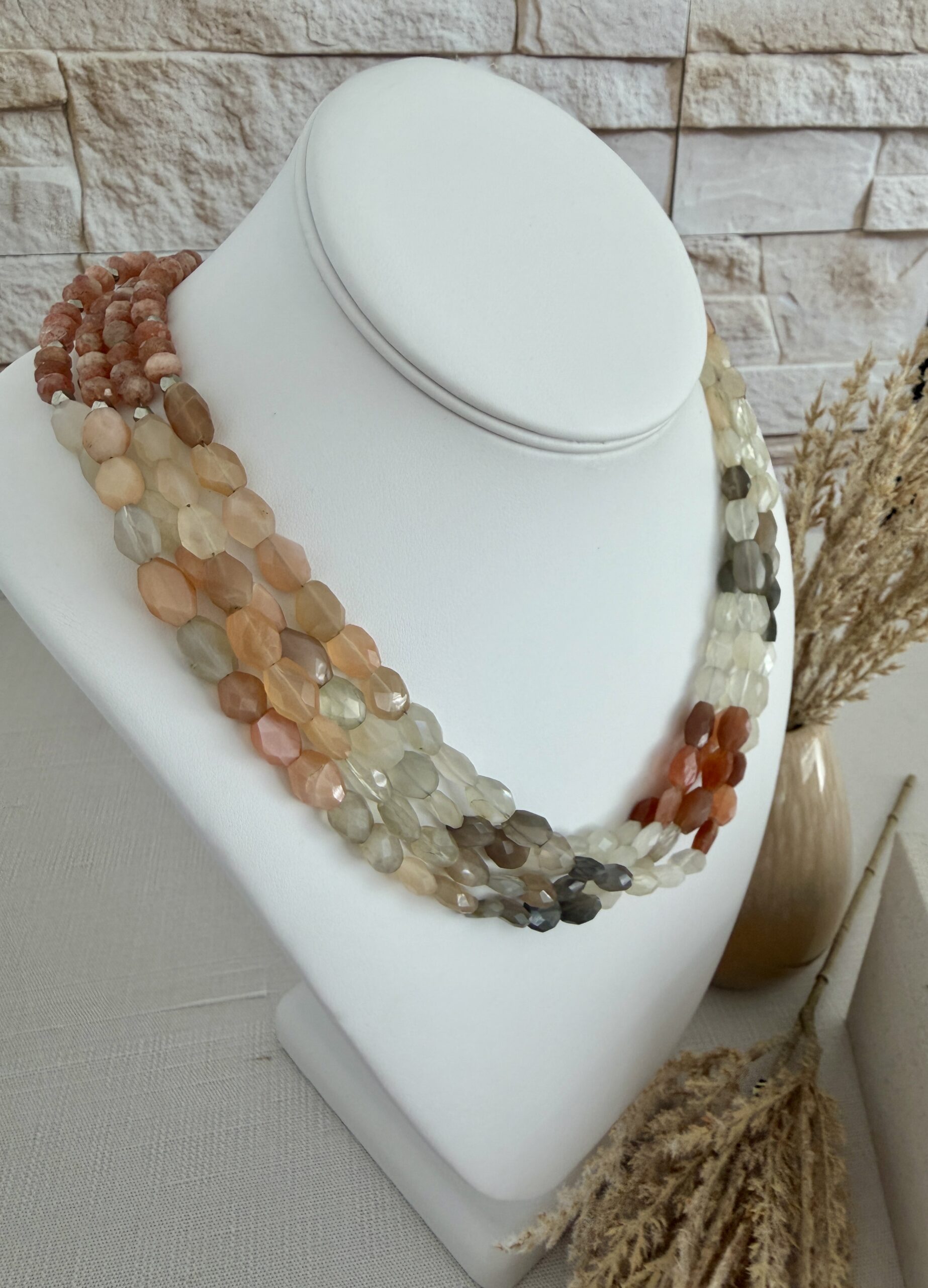Four strands of three colors of moonstone beads layered as one necklace. The colors are rust/peach ivory and brown. The necklace is approxamately 18” long and has a lobster claw clasp.