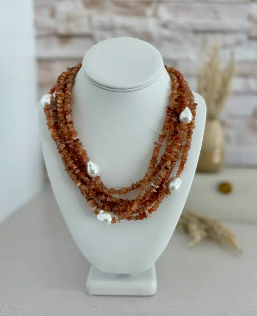 6 layers of rose quartz gemstones in chip cut beads. The necklace also has baroque pearls scattered throughout. The clasp is in silver and is an oversized lobster claw closure. It is approxamately 18” in length
