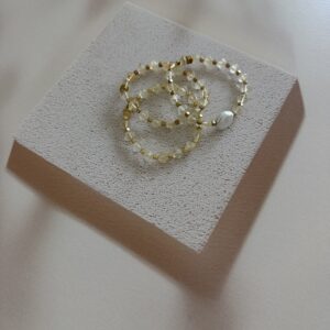 A set of three stretch bracelets made of citrine. The bead shape is a bicone. One bracelet has a coin shaped baroque pearl as its focal. It is sold as a set.